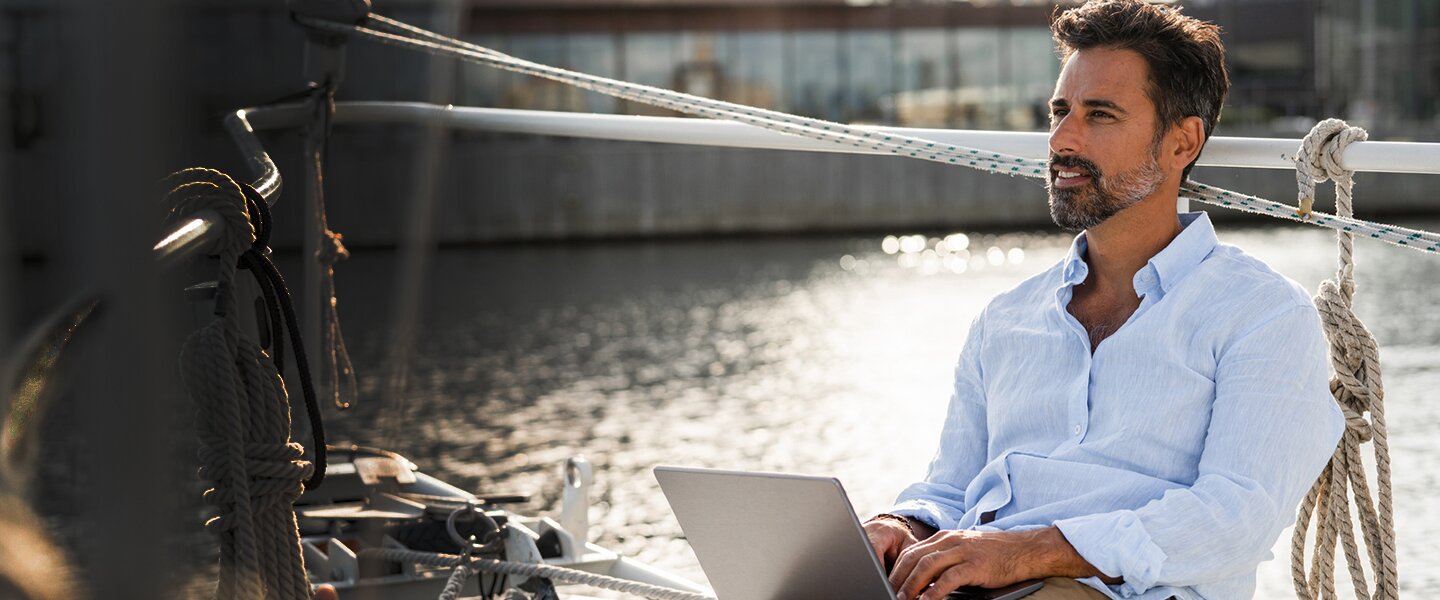 Ein freier, unabhängiger Versicherungsmakler, der mit Laptop am Wasser sitzt