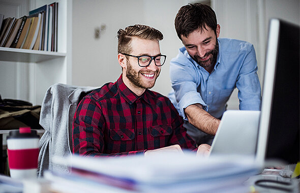 Zwei junge Männer, die am Rechner sitzen und erste Berufserfahrungen als Werkstudent und Praktikant sammeln