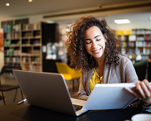 Eine Frau, die am Laptop sitzt und ihre Bewerbungsunterlagen für ihre Bewerbung bei der Fonds Finanz in München zusammenstellt