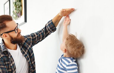 Ein Mann, der seinem kleinen Sohn zeigt, wie groß gewachsen er schon bald sein wird