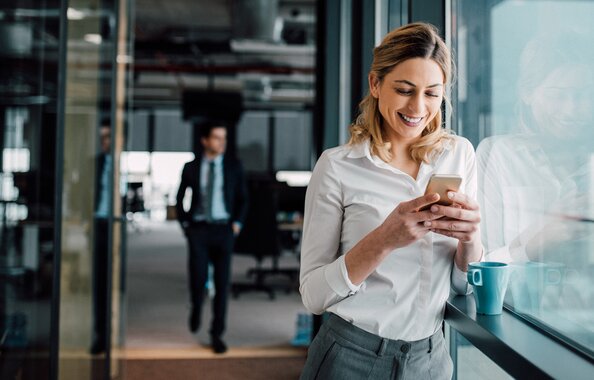 Eine Frau, die sich mit ihrem Handy für den Newsletter der Fonds Finanz registriert