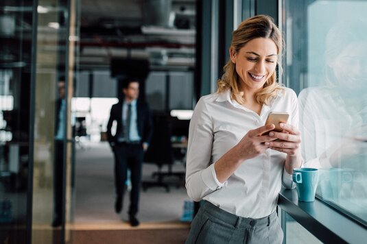 Eine Frau, die sich mit ihrem Handy für den Newsletter der Fonds Finanz registriert