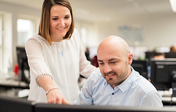 Mitarbeiter der Fonds Finanz beim Schulterblick am Monitor