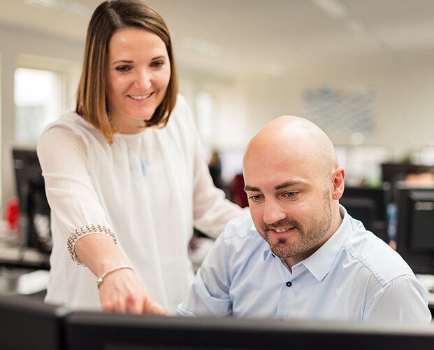 Mitarbeiter der Fonds Finanz beim Schulterblick am Monitor