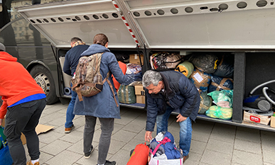 Helfer vor einem Reisebus beim Packen von Hilfsgütern für Menschen in der Ukraine